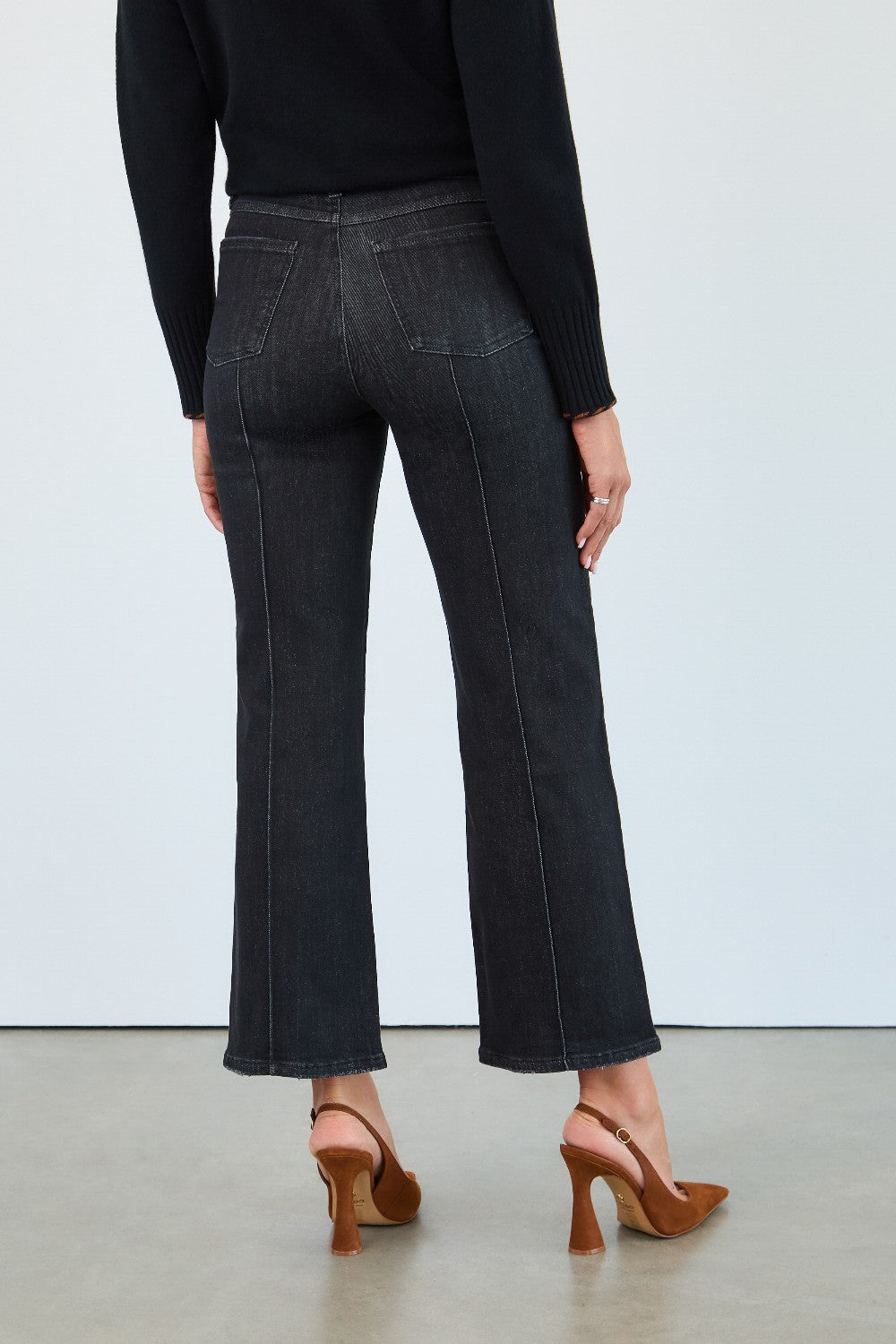 Person wearing black jeans and a black top on a white background