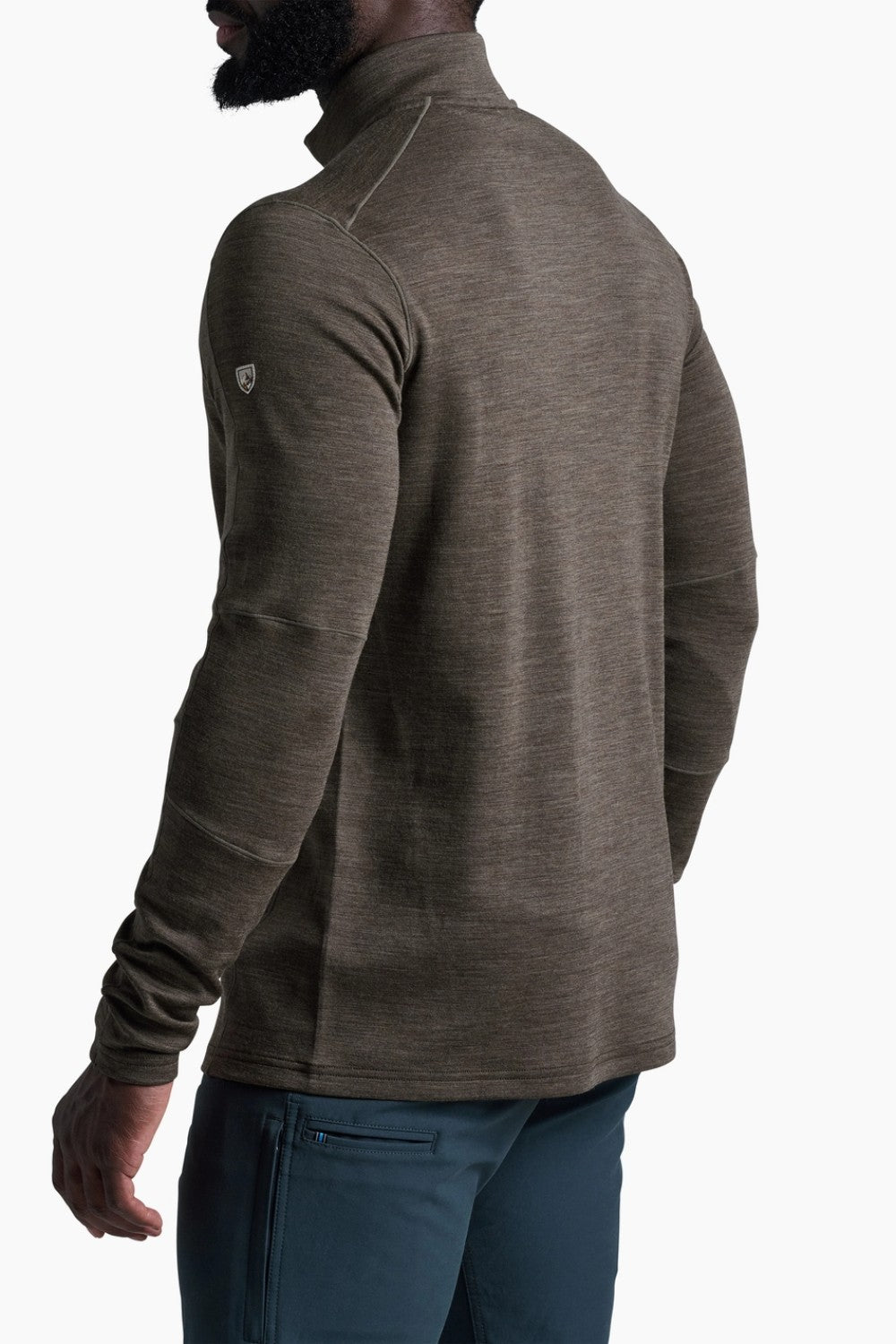 Man wearing a brown long-sleeve shirt with a small logo on the chest against a white background