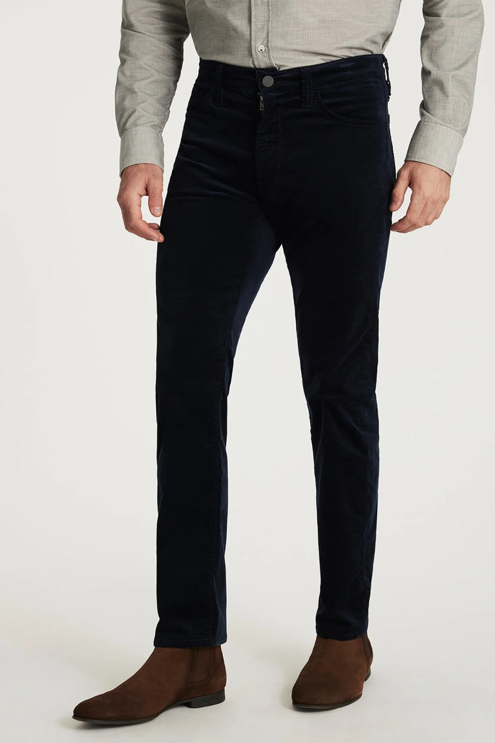 Person wearing dark blue jeans and brown shoes on a white background