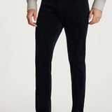Person wearing dark blue jeans and brown shoes on a white background