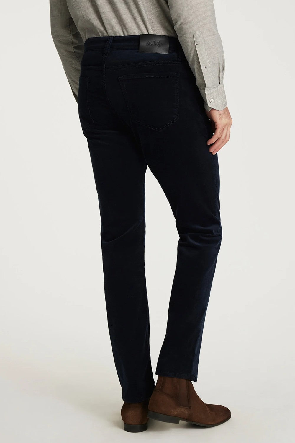 Person wearing dark blue pants and brown shoes on a white background