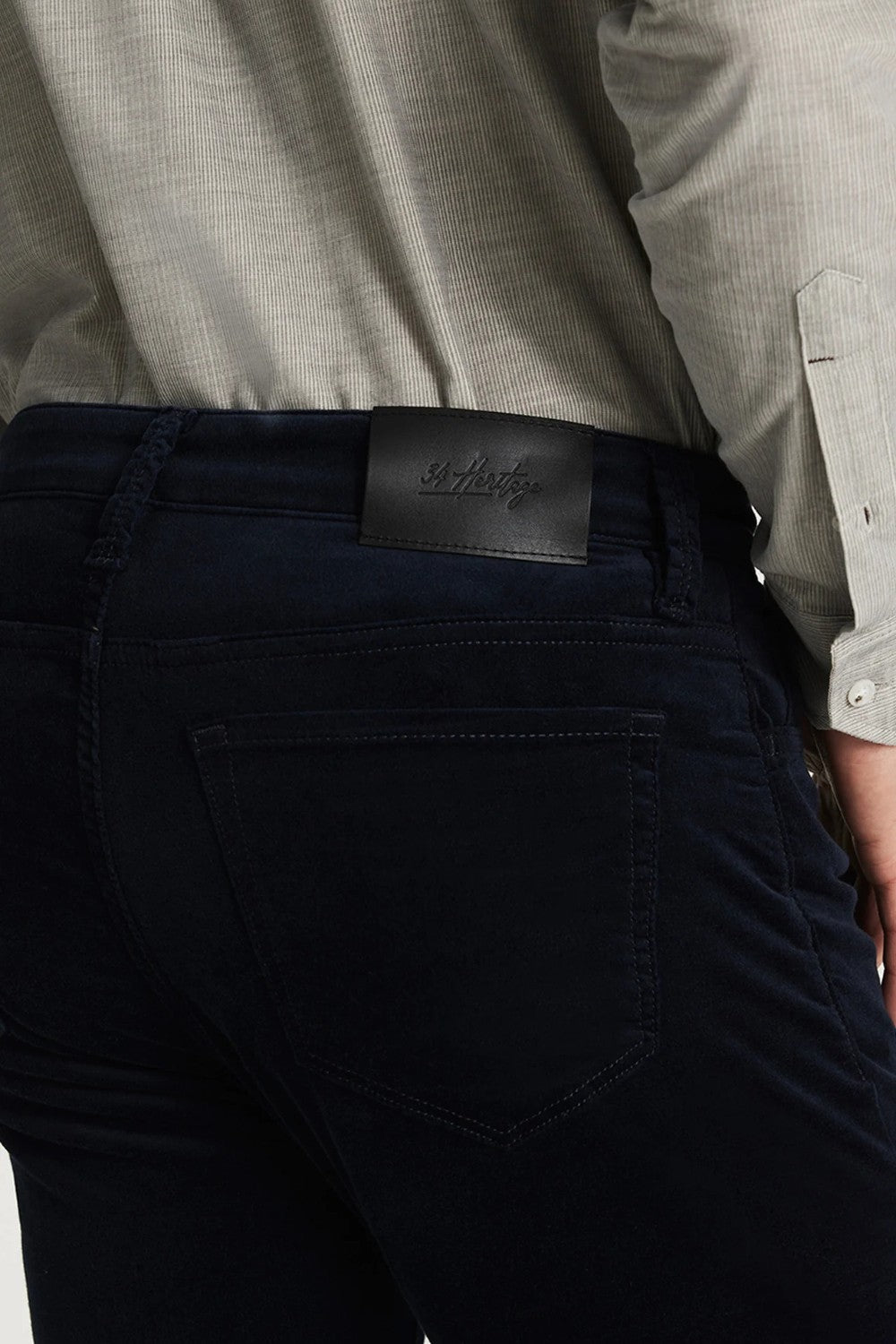 Person wearing dark blue pants with a visible brand logo on the waistband.