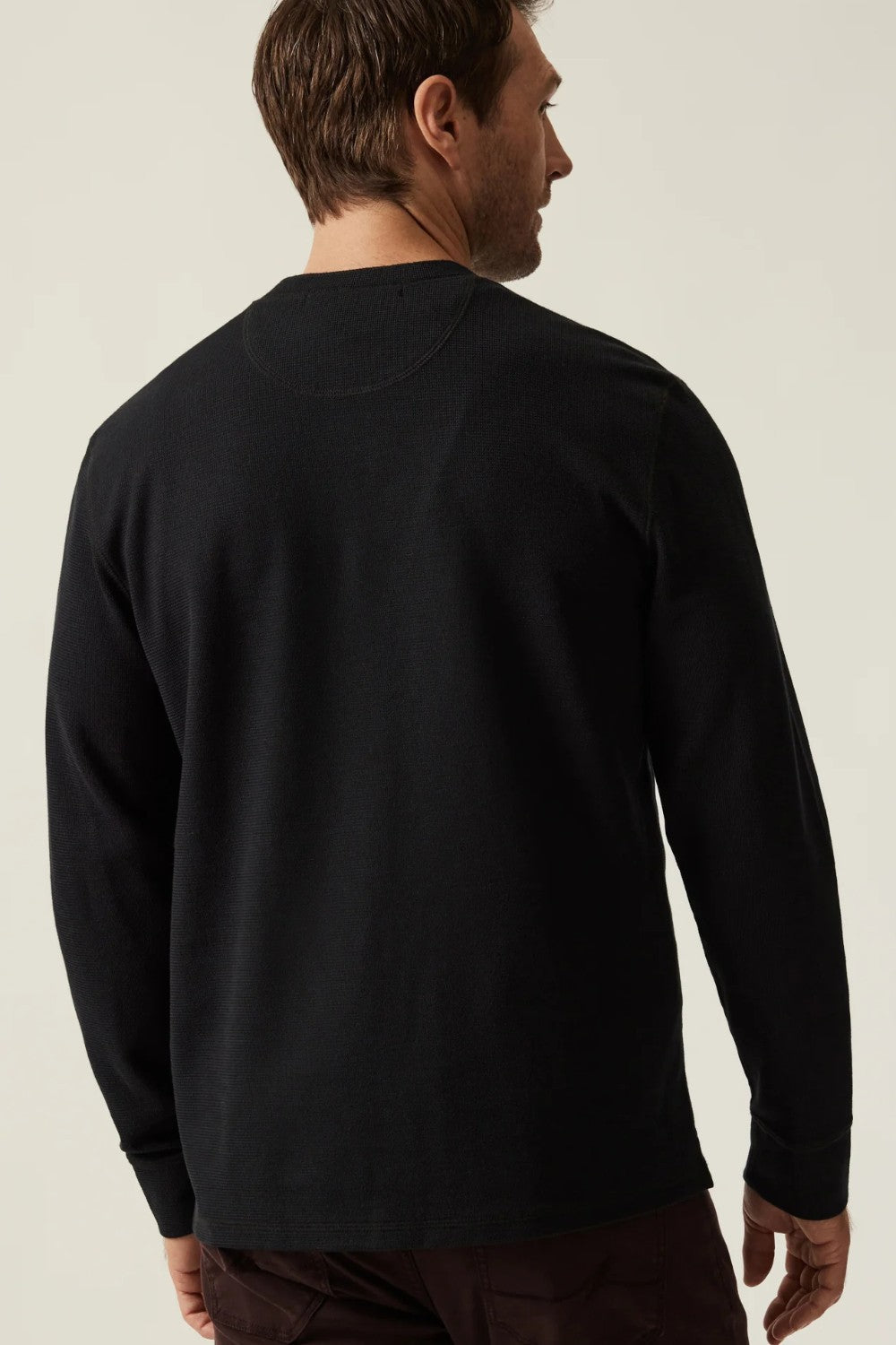 Man wearing a black long-sleeve shirt against a plain background