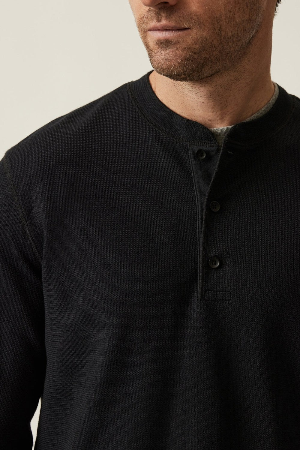 Man wearing a black long-sleeve shirt against a neutral background