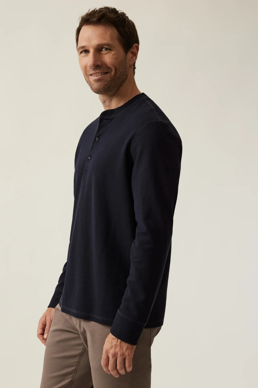 Man wearing a dark blue long-sleeve shirt against a plain background