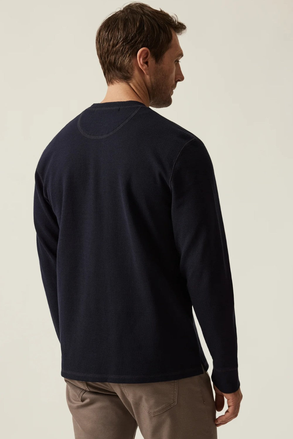 Man wearing a navy long-sleeve shirt on a beige background