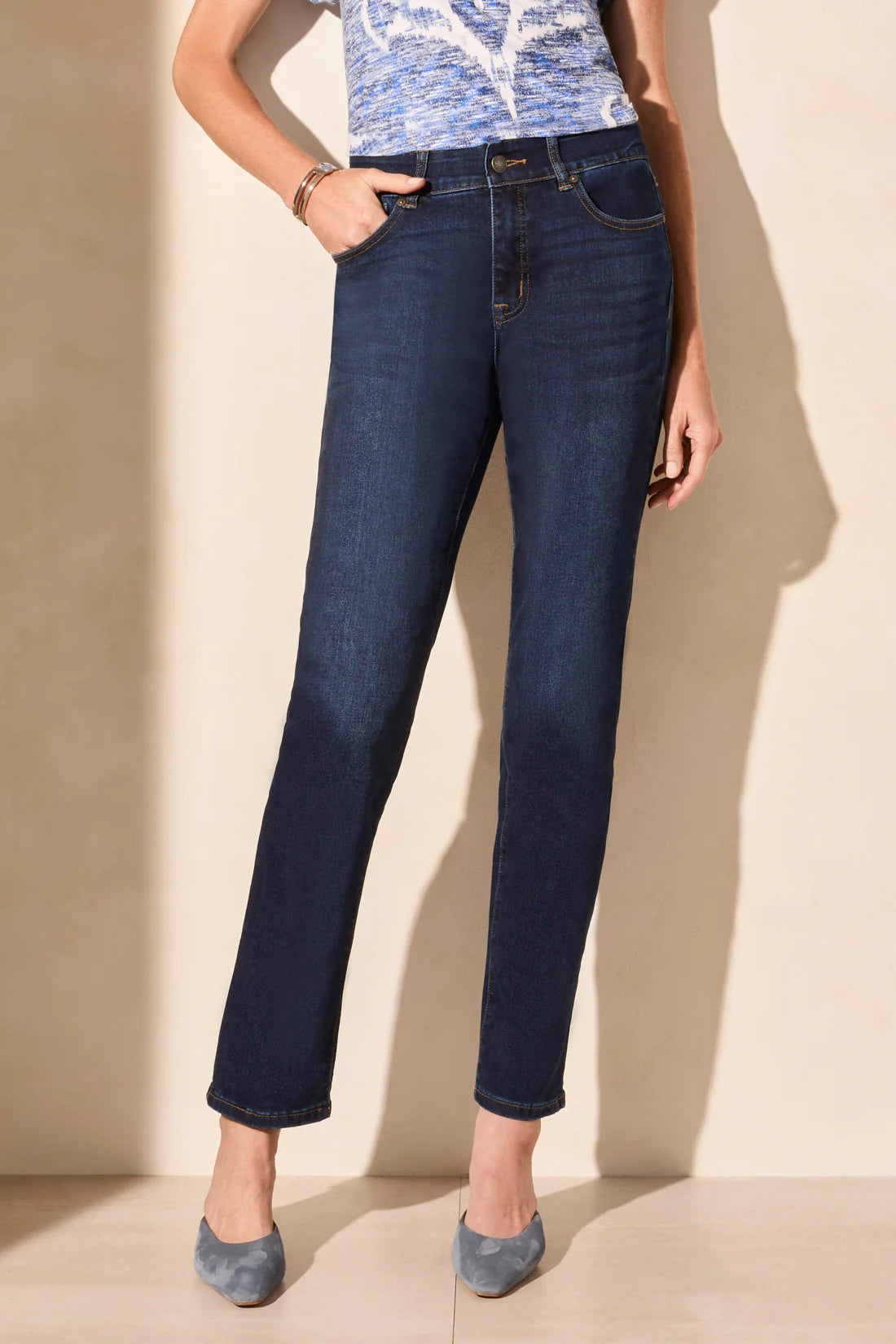 Person wearing dark blue jeans against a beige background
