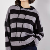 Woman wearing a black and gray striped poncho against a white background