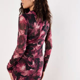 Woman wearing a long-sleeve, patterned dress against a white background