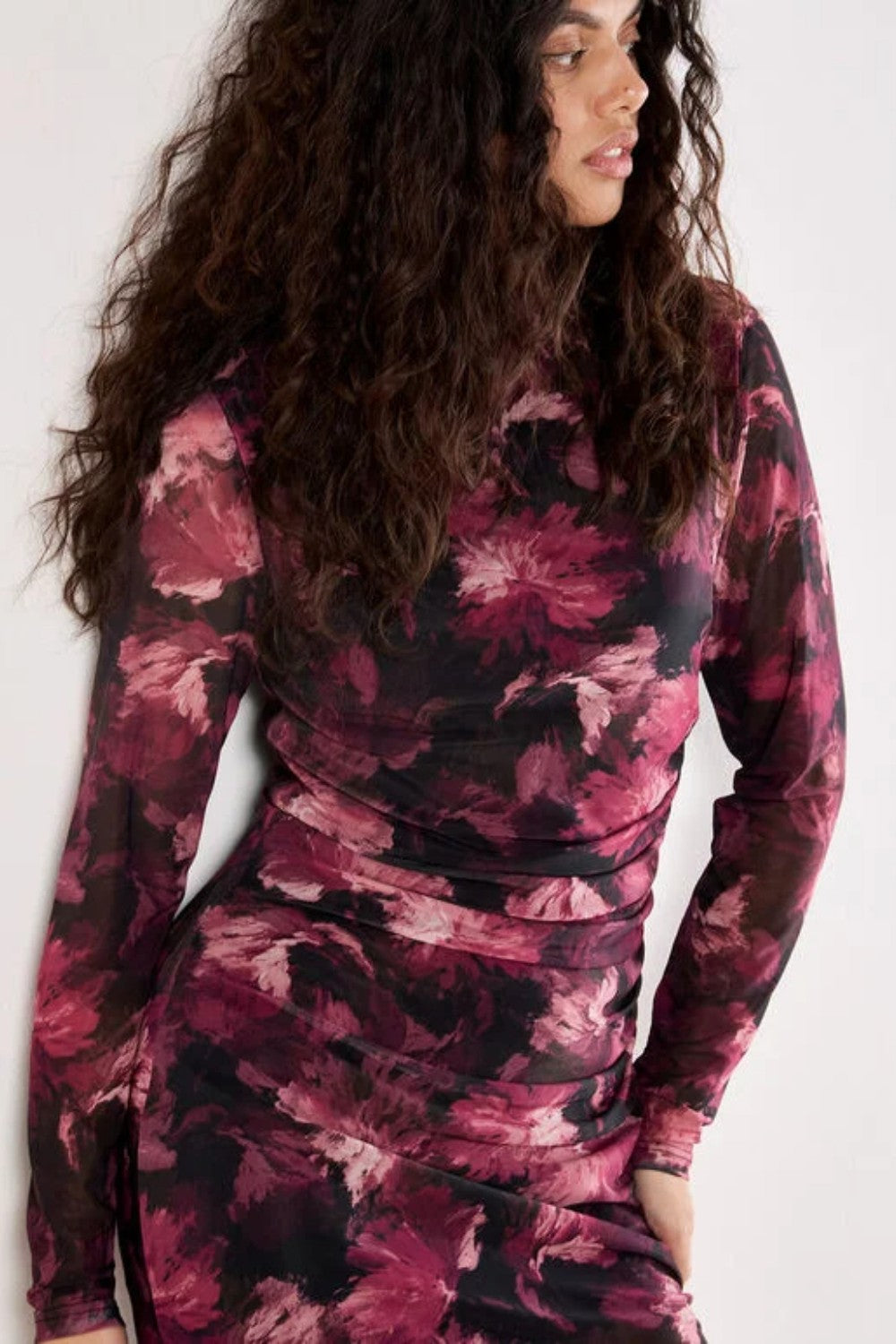 Woman wearing a long-sleeve, patterned dress against a white background