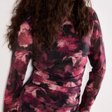 Woman wearing a long-sleeve, patterned dress against a white background