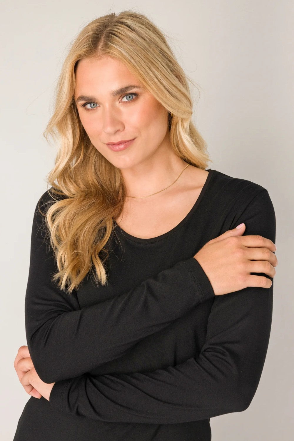 Woman wearing a black long-sleeve top against a plain background