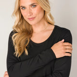 Woman wearing a black long-sleeve top against a plain background