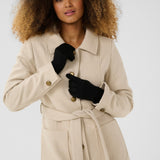 Woman wearing a beige trench coat and black gloves on a white background