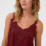 Woman wearing a burgundy sleeveless top with lace detailing on a white background