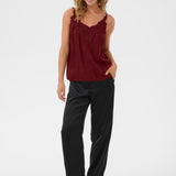 Woman wearing a burgundy top and black pants on a white background