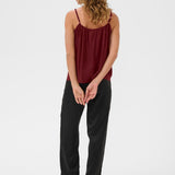Woman wearing a burgundy top and black pants on a white background