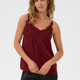 Woman wearing a burgundy sleeveless top with lace details on a white background