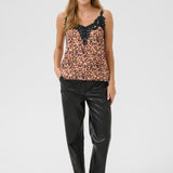 Woman wearing a leopard print top and black pants on a white background