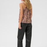 Woman wearing a leopard print top and black pants on a white background