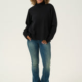 Person wearing a black turtleneck and blue jeans on a white background