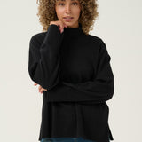 Woman wearing a black turtleneck sweater and blue jeans against a white background