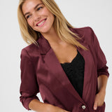 Woman wearing a burgundy satin jacket on a white background