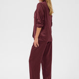 Woman wearing a burgundy satin outfit on a white background