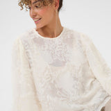 Woman wearing a white lace top against a white background