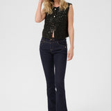 Woman wearing a black sequin top and dark jeans on a white background