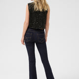 Woman wearing black sequin top and dark jeans on a white background
