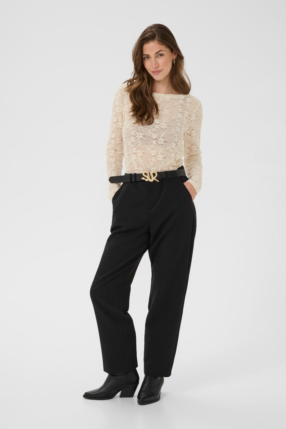 Woman wearing a beige sweater and black pants on a white background