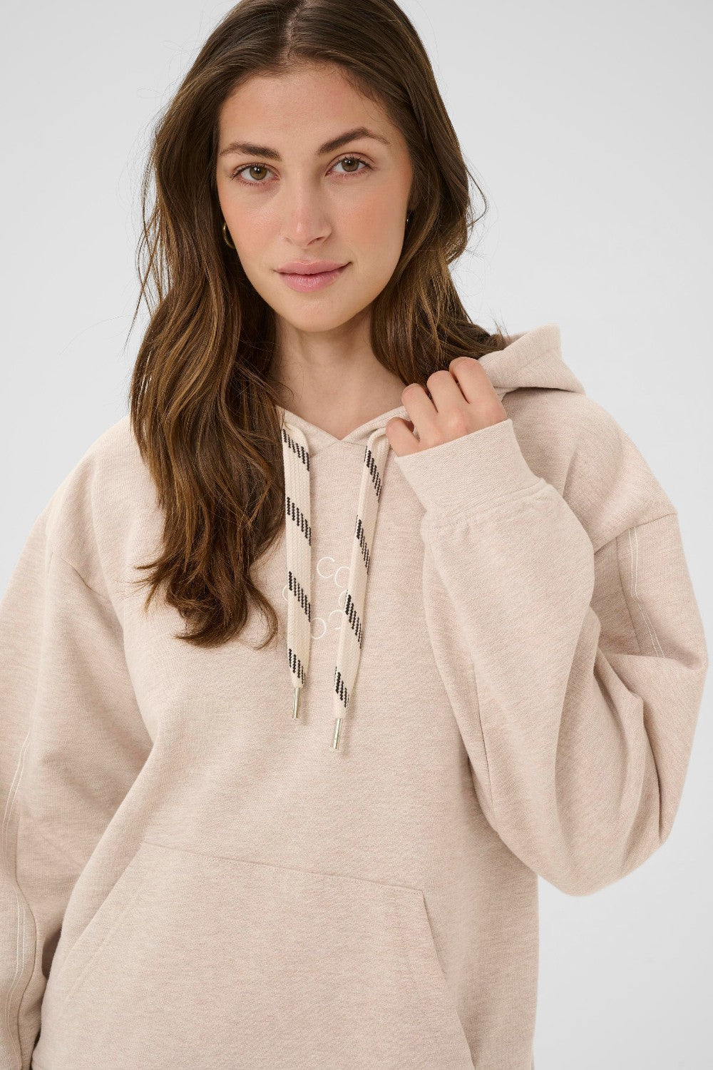 Woman wearing a beige hoodie against a white background