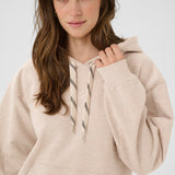 Woman wearing a beige hoodie against a white background