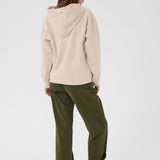 Person wearing a beige hoodie and green pants on a white background