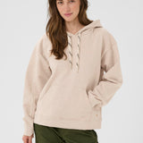 Woman wearing a beige hoodie and green pants on a white background