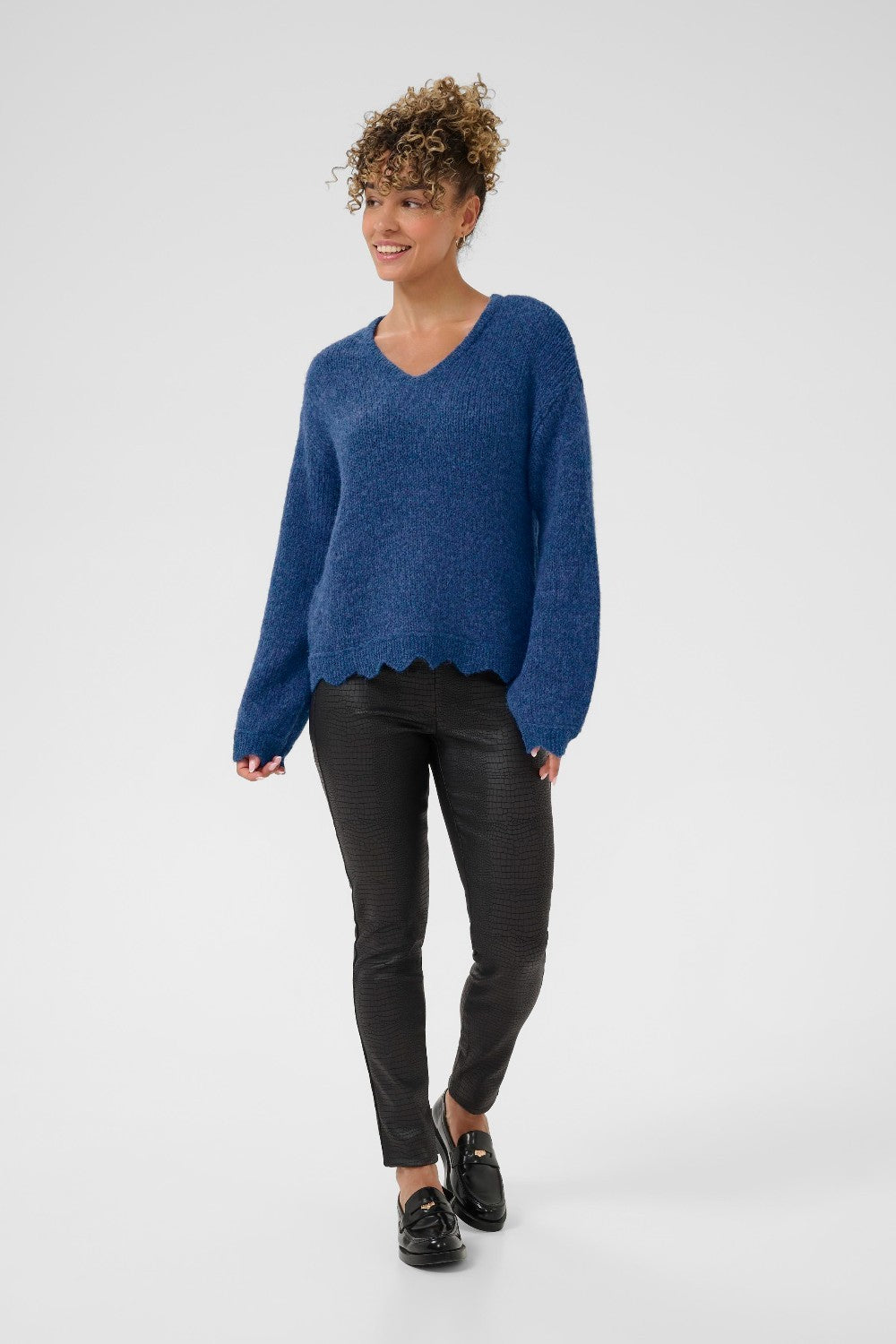 Woman wearing a blue sweater and black pants on a white background
