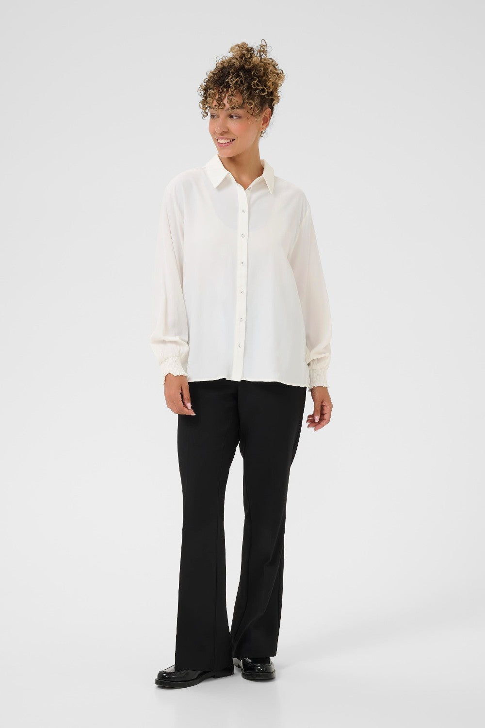 Person wearing a white shirt and black pants on a white background