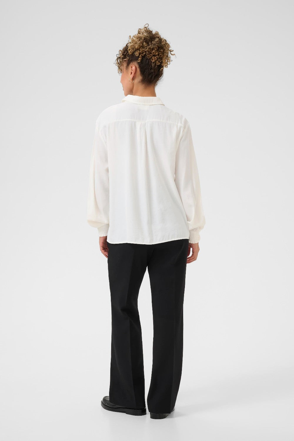 Person wearing a white shirt and black pants on a white background