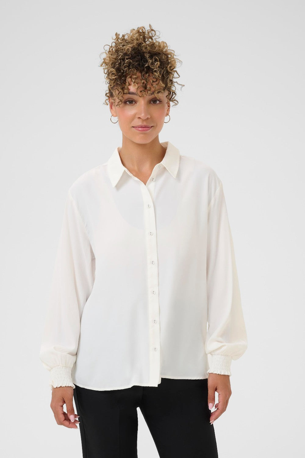 Woman wearing a white blouse against a plain background