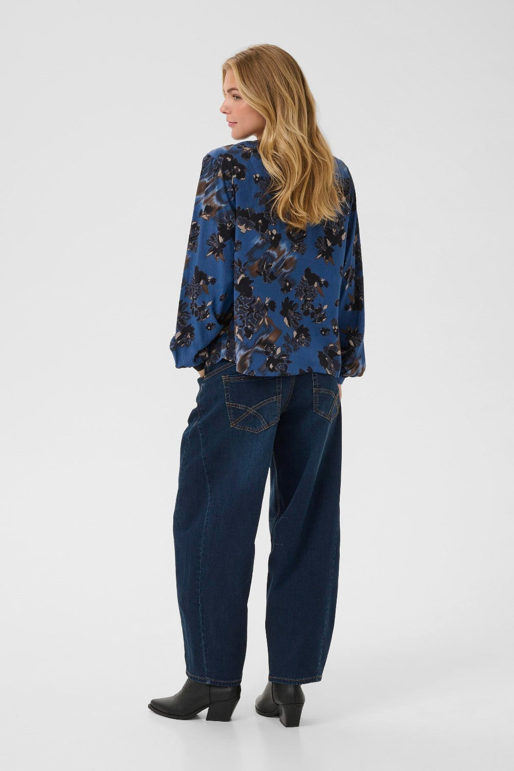Woman wearing a blue floral shirt and jeans on a white background