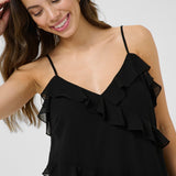 Woman wearing a black ruffled top against a white background