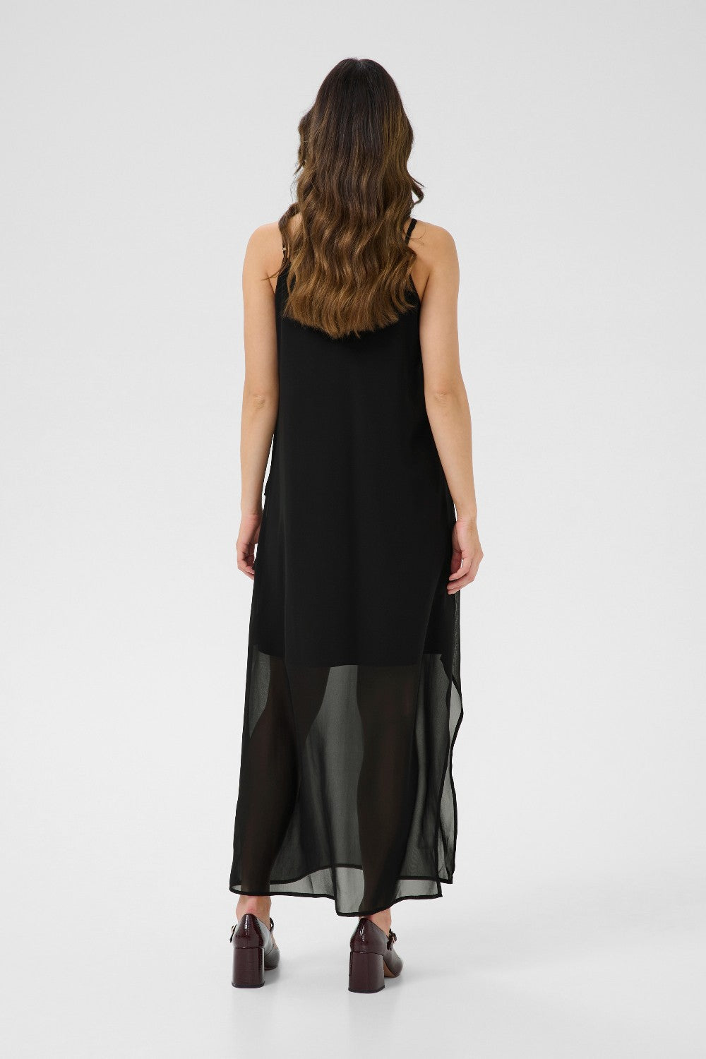 Woman wearing a black dress with sheer overlay on a white background