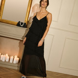 Woman in a black dress standing in a room with candles and a mirror.