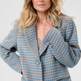Woman wearing a blue houndstooth patterned coat on a white background