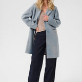 Woman wearing a checkered coat over a sweater and pants on a white background