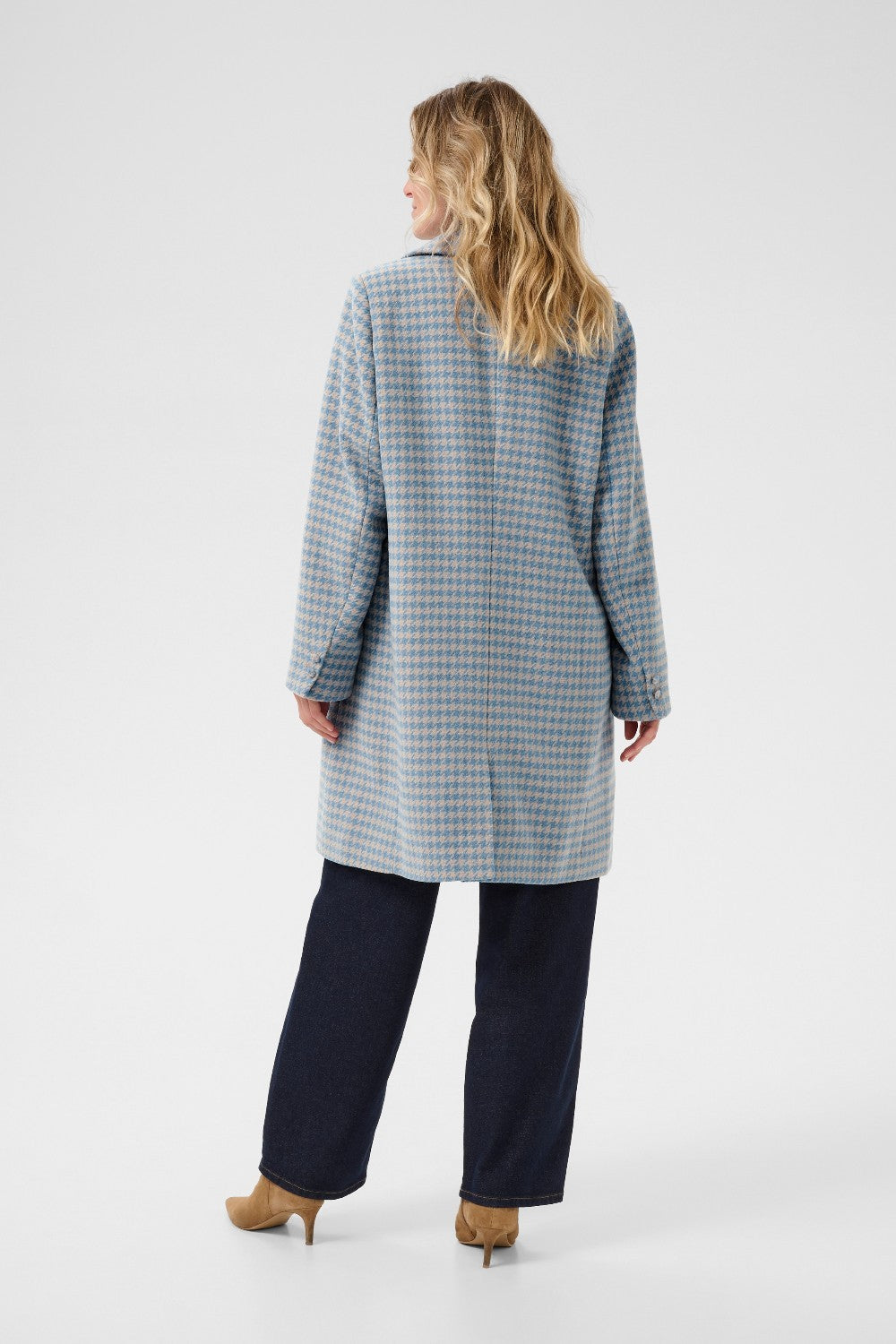 Woman wearing a long, checkered coat on a white background