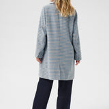 Woman wearing a long, checkered coat on a white background