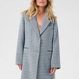 Woman wearing a blue checkered coat against a white background
