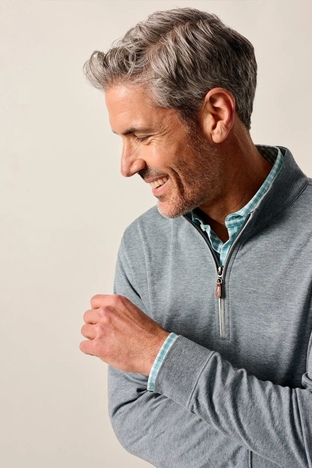 Man wearing a gray zip-up sweatshirt against a plain background